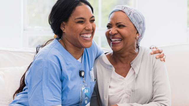 Female Cancer patient laughing with Nurse and holding hands