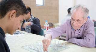 An older man playing chess with a younger man