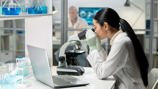 Female research looking into a microscope