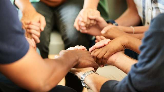 Group of men in a support group in a circle and holding hands