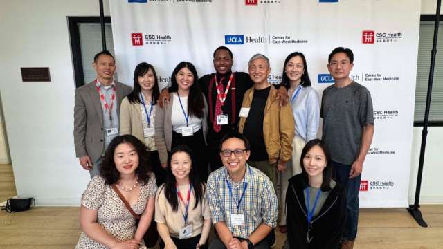Group photo of 11 smiling participants posing together in front of a step-and-repeat banner.