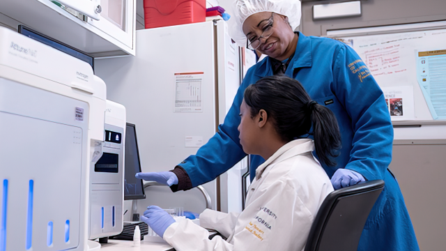 Two people use flow cytometry equipment in the UCLA Health Flow Cytometry Shared Resource laboratory for advanced cell analysis.