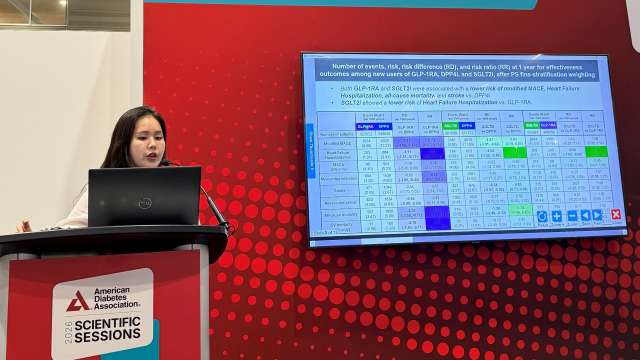 Presenter at ePOSTER Theater B podium beside large screen displaying poster schedule