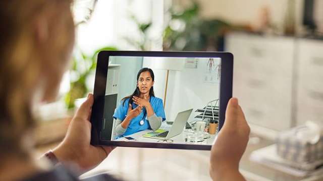 elderly woman holding an ipad on a video call with a medical professional for a telemedicine appointment