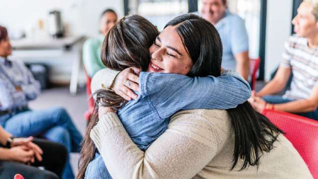 Two women hugging at a support group meeting