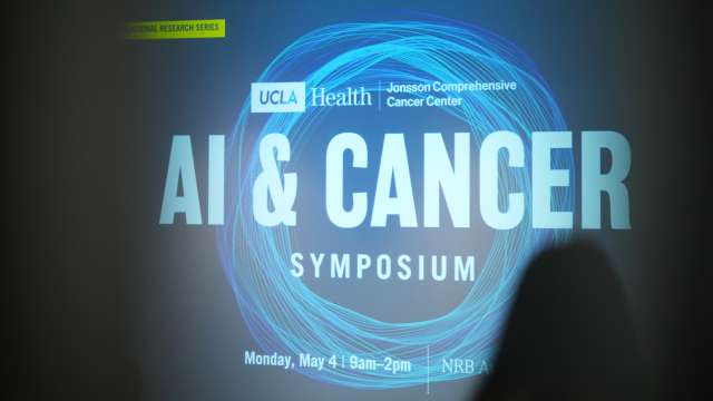 Silhouettes of cancer researchers standing in front of a digital sign that says "Ai & Cancer Symposium"