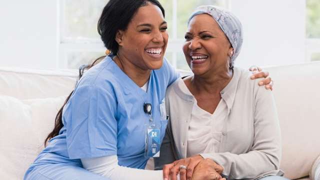 A smiling nurse sits next to a smiling patient.