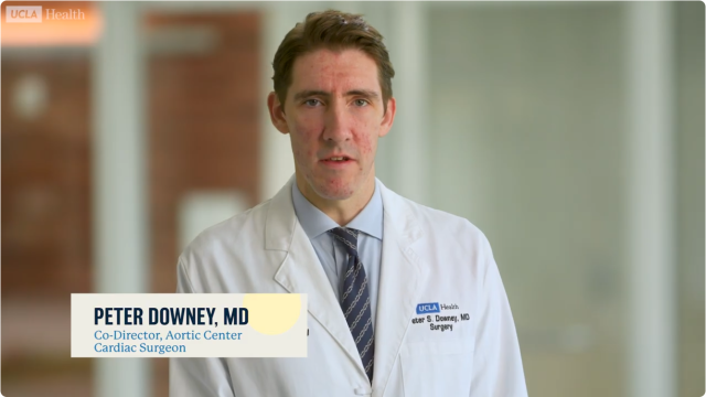 Medical doctor in white coat and tie with on-screen nameplate