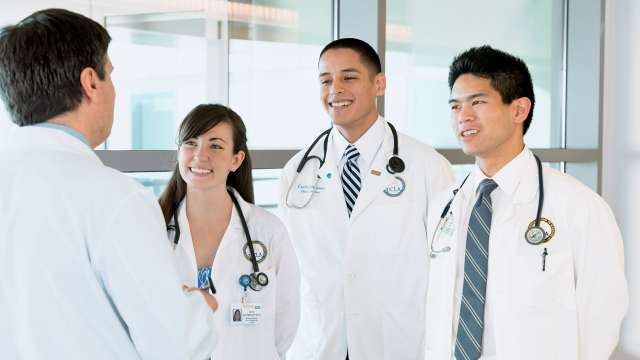 Medical students smiling and looking at a teacher.