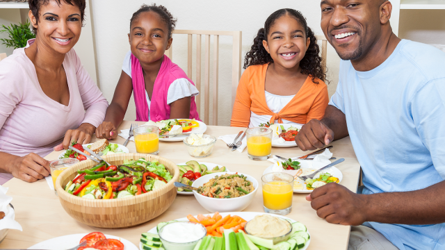Smiling family enjoying a colorful, healthy meal together at home, promoting balanced nutrition and wellness through shared meals.