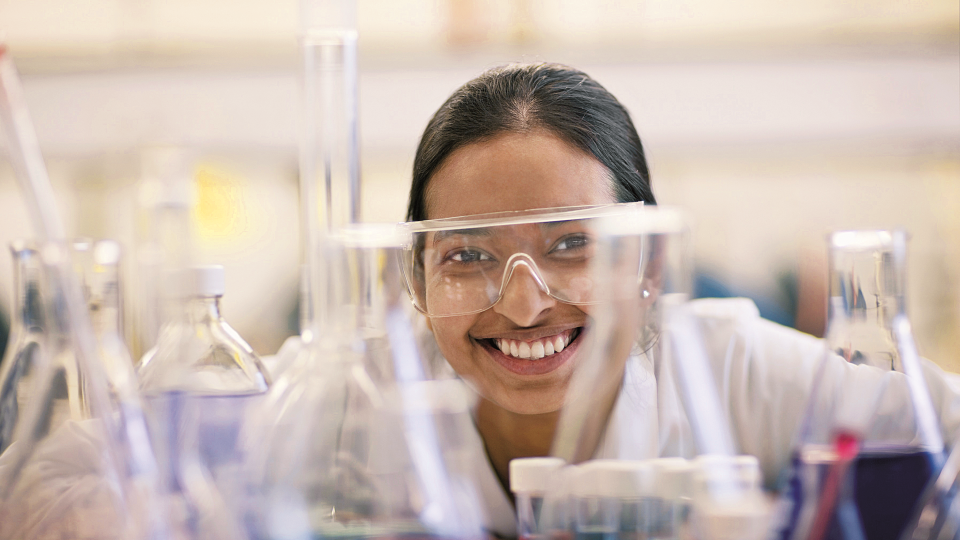 Woman smiling in lab wearing protective glasses