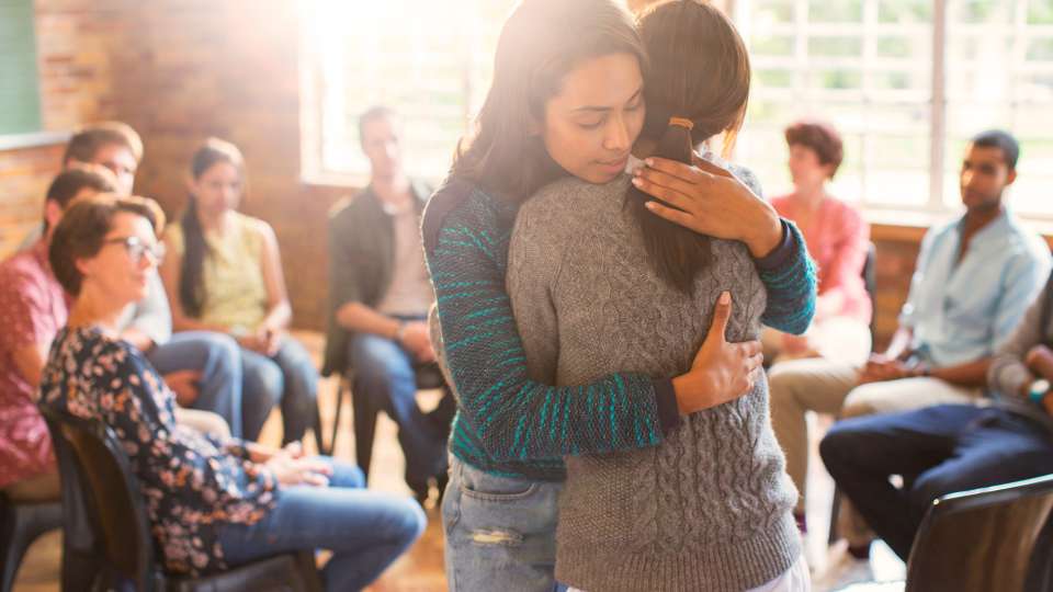 Two people hugging in a support group