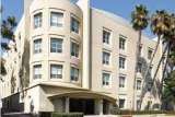 Berkley East building with curved corner facade and palm trees.