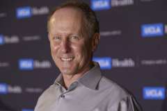 Dr. Eric Daar in a gray shirt stands in front of a UCLA Health backdrop.
