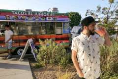 Niko Massaly, PhD, sipping a drink in front of a Tacos El Junior truck