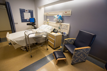 Postpartum Room with hospital bed, baby crib, and a sofa - used for recovery and bonding.