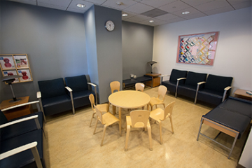 Family Waiting Room. Rounded wooden table with chairs, surrounded by seven armchairs.