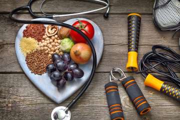 Fruits on a heart shape plate, workout equipment, and stethoscope.