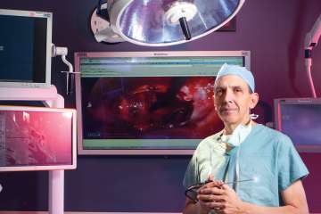 A doctor holding a tool in an operating room with multiple screens,