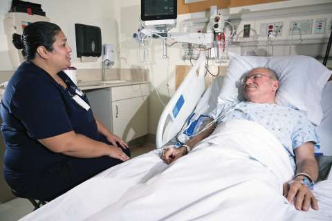 Nurse speaking with a patient in a hospital room.