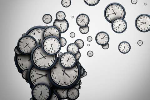 Silhouette of a human head made of many analog clocks with clocks drifting away.
