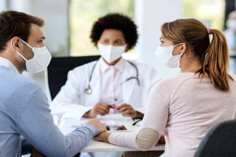 Couple in masks consulting doctor about fertility