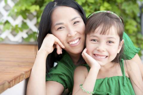 A mother hugs her daughter, both smiling