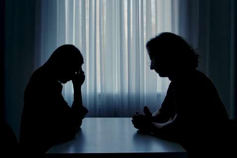 Silhouette of two people talking.