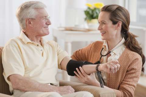 Nurse taking senior man's blood pressure
