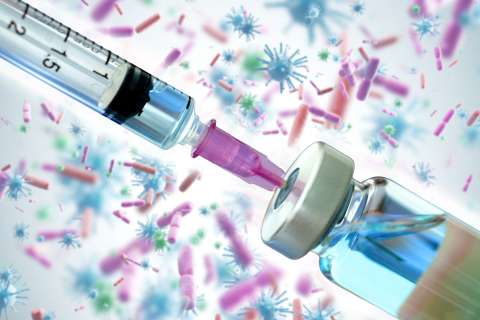 An illustration shows a vaccine in front of a background of cells.