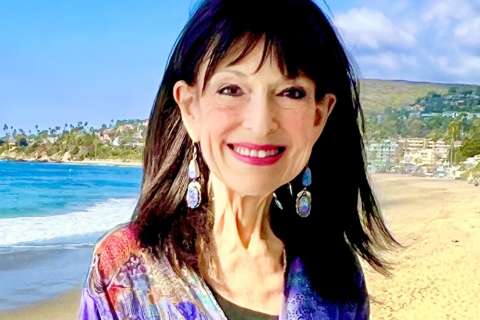 Debra Gold stands with the coastline in the background.