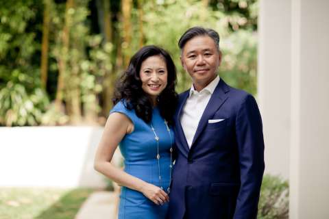 Smiling man in navy suit and woman in blue dress standing outdoors