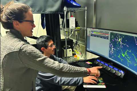 Two people at a lab computer pointing at screens showing molecular models