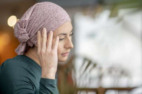 Woman wearing a headscarf touching her ear and looking downward