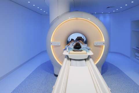 Patient supine with head inside a circular MRI scanner on a sliding table.