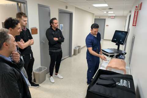 Instructor demonstrating paracentesis on a mannequin while a small group watches