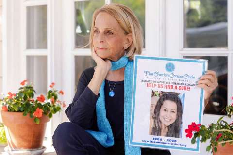 Paulinda Schimmel Babbini sitting on a porch, holding a photo of her daughter.
