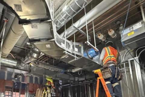 A crew member installs the HVAC system at Mid-Wilshire