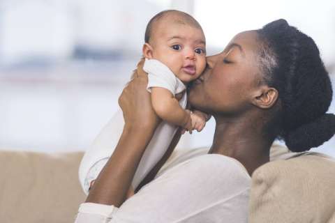 Close-up showing a woman kissing her baby, highlighting the loving connection between them