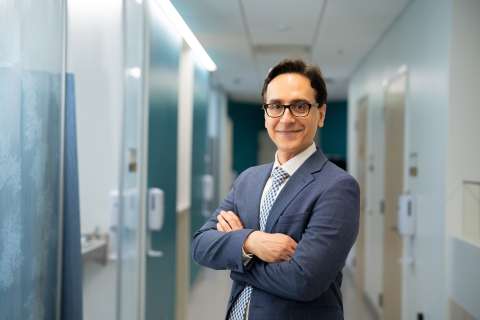 Dr. Amir Iravani in suit with arms crossed in office hallway.