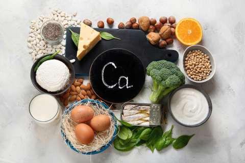 Assorted calcium-rich foods arranged around a chalkboard labeled "Ca".