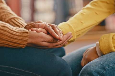 A caregiver holds a person's hand.