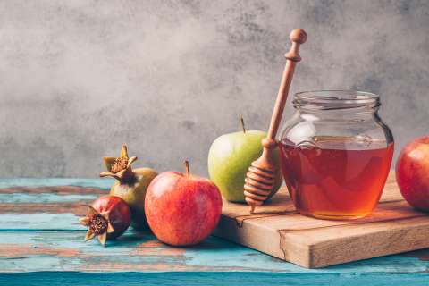 A glass jar filled with honey sitting on a cutting board