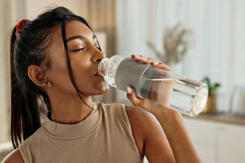 Woman drinking water from a reusable bottle
