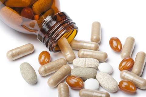 brown medicine bottle spilling beige tablets and amber softgels
