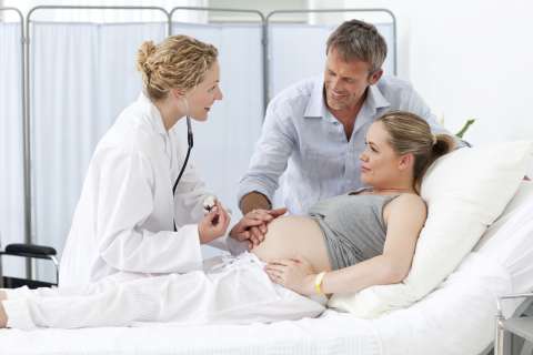 Pregnant woman with father in hospital talking to a doctor