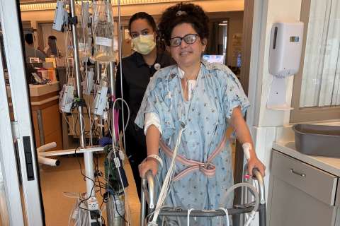 A patient walks through a hospital using a walker.