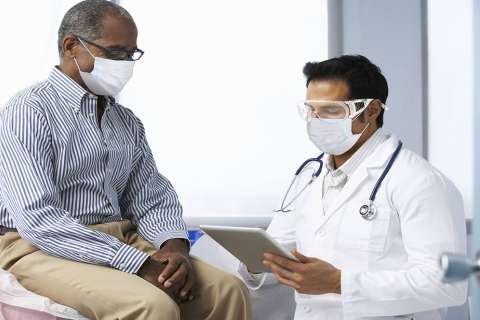 Doctor and patient in hospital setting discussing diagnosis using a tablet