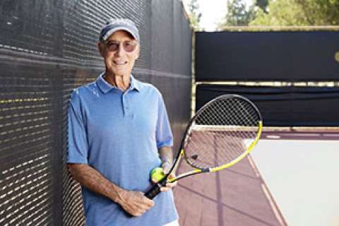 Tom Stutz stands with a tennis racket on a court.
