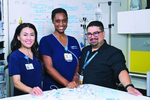 Three healthcare professionals in uniforms standing by a table with medical supplies.